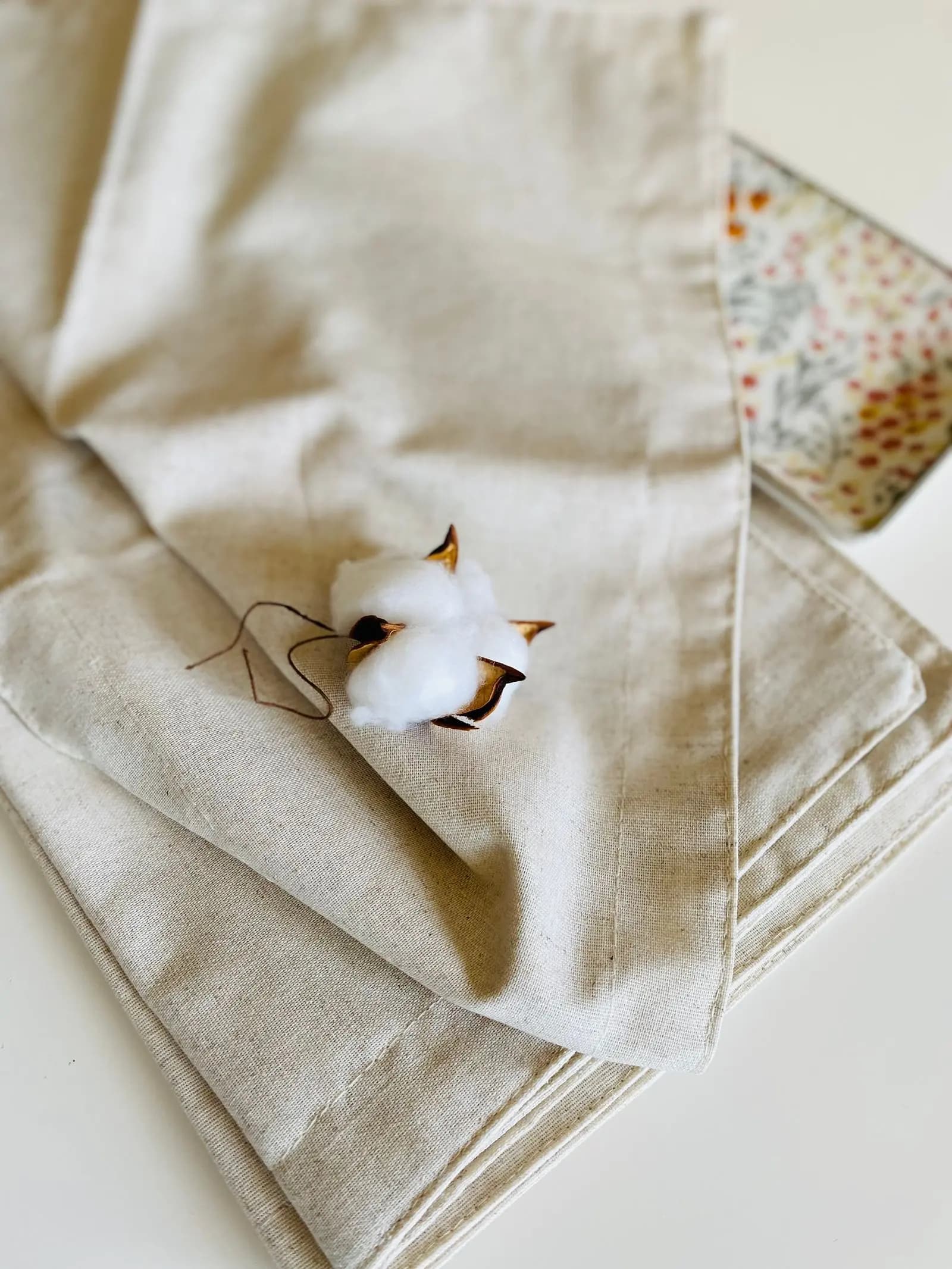 Cotton boll resting on natural beige linen fabric