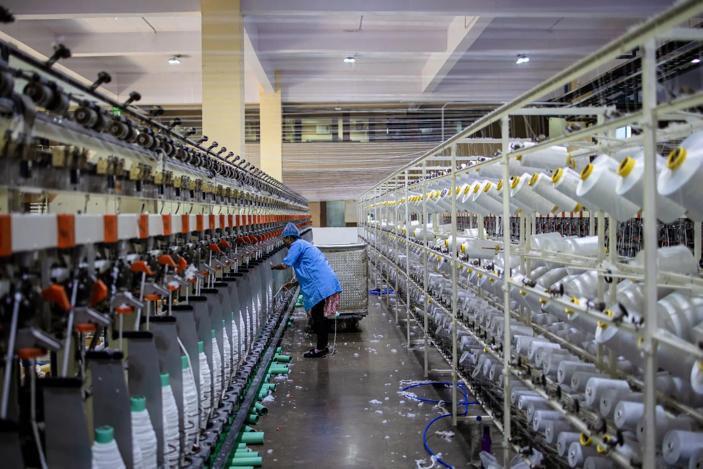 Rows of white cotton yarn cones on spinning machines in a textile mill
